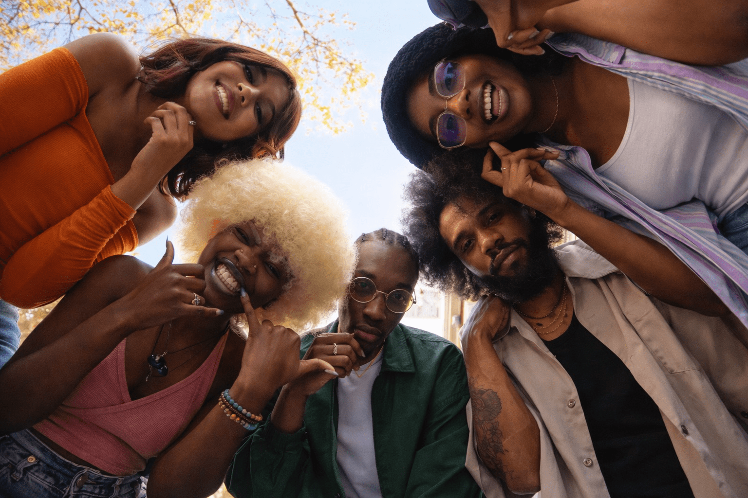 Six University of Cape Town students standing in a circle, looking down at the camera against a bright sky, symbolising diversity and togetherness.