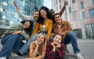 A group of young adults from minority ethnic communities in the United Kingdom gathered together in a modern urban setting, smiling and posing closely to convey friendship and belonging.