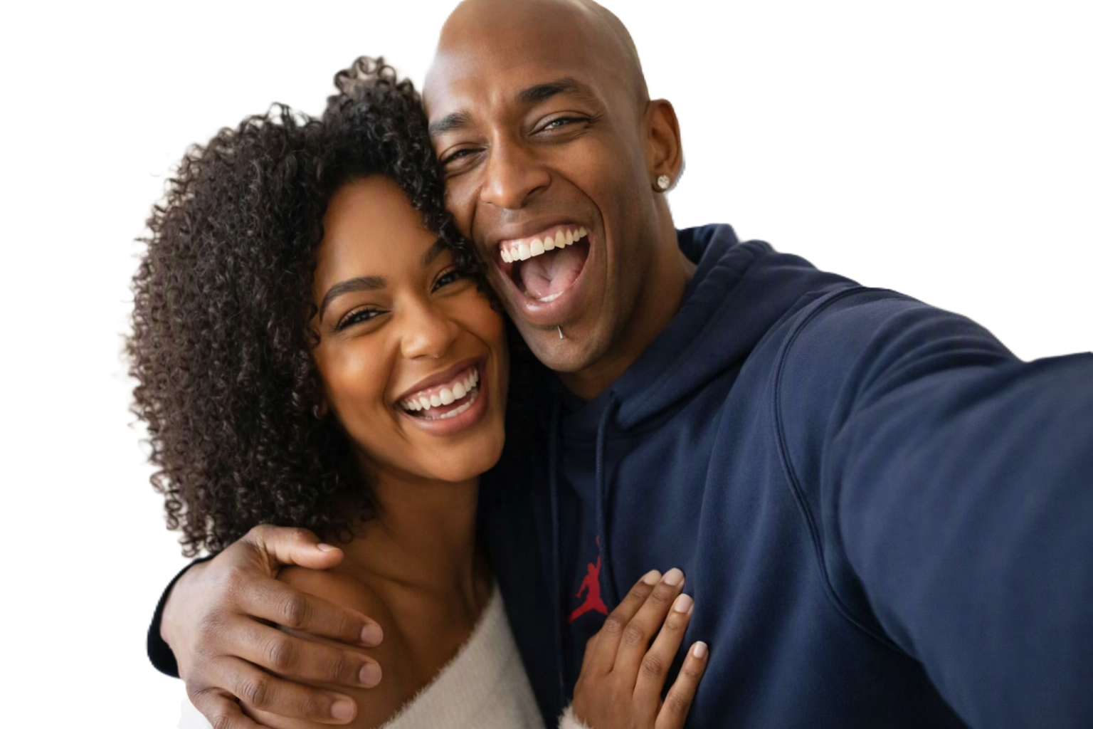 Sola and Peter stand close together in their London living room, smiling brightly at the camera. Sola wears a light top with curly hair framing her face, while Peter wears a dark blue hoodie with a red logo. The plain white background highlights their joyful expressions and closeness.