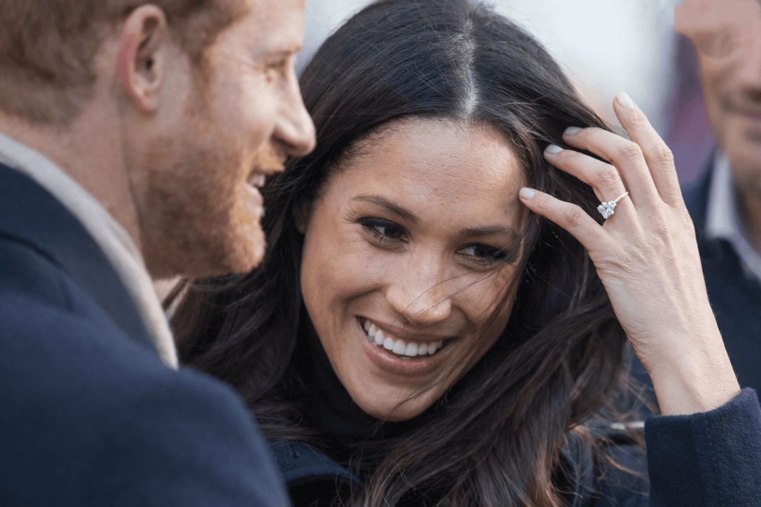 Prince Harry and Meghan Markle smiling outdoors, representing their decision to move back to Britain with their children.