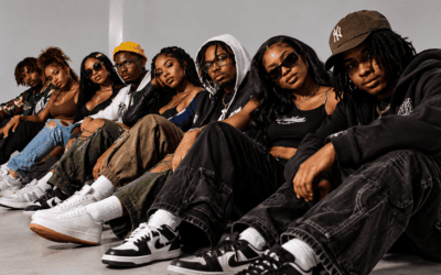 Group of young Black people seated together in a modern studio, wearing contemporary streetwear and sneakers.