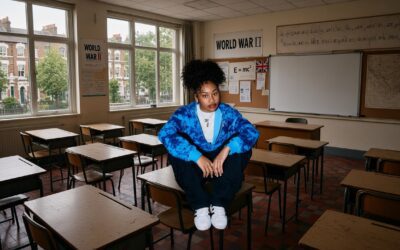 A young student sitting alone in an empty London classroom, illustrating falling school enrolment and concerns about families leaving the capital.