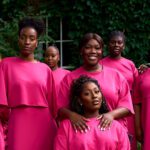 The Spirituals Choir UK members during a group portrait session in matching pink attire outdoors