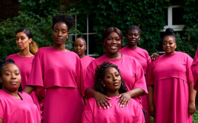 The Spirituals Choir UK members during a group portrait session in matching pink attire outdoors