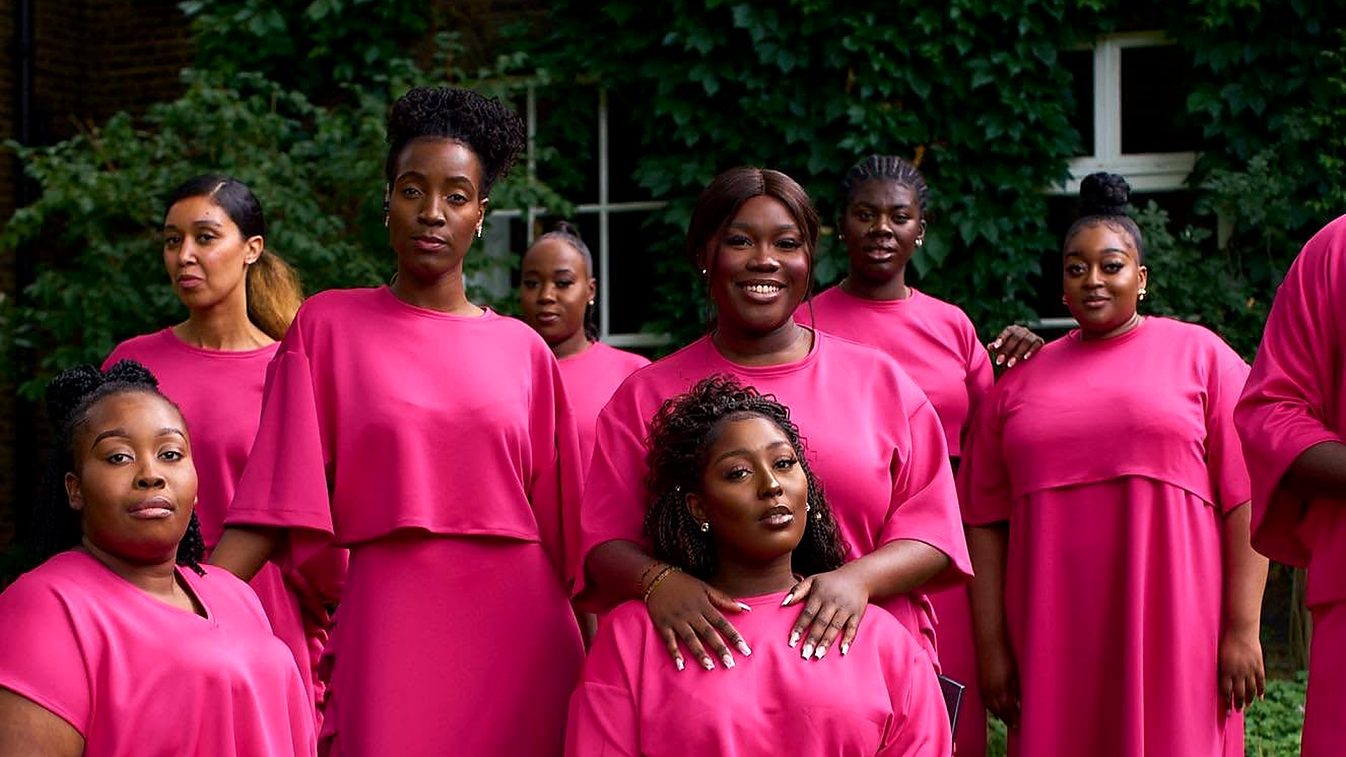 The Spirituals Choir UK members during a group portrait session in matching pink attire outdoors